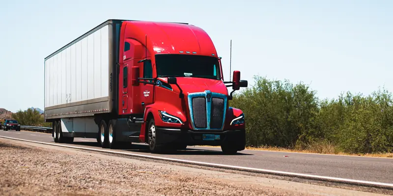 Red semi truck driving on an open highway